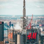Cityscape of a tall skyscraper with H & M advertised on it.