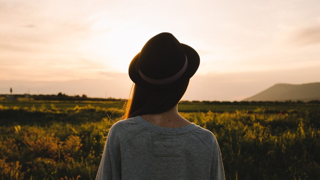 woman with hat facing sunrise