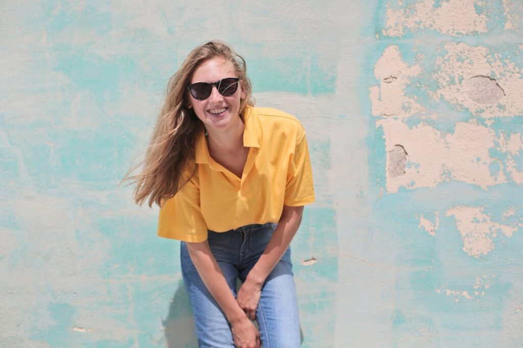 Woman wearing yellow polo shirt standing in front of teal concrete wall