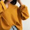 a woman in a yellow sweater is holding her head