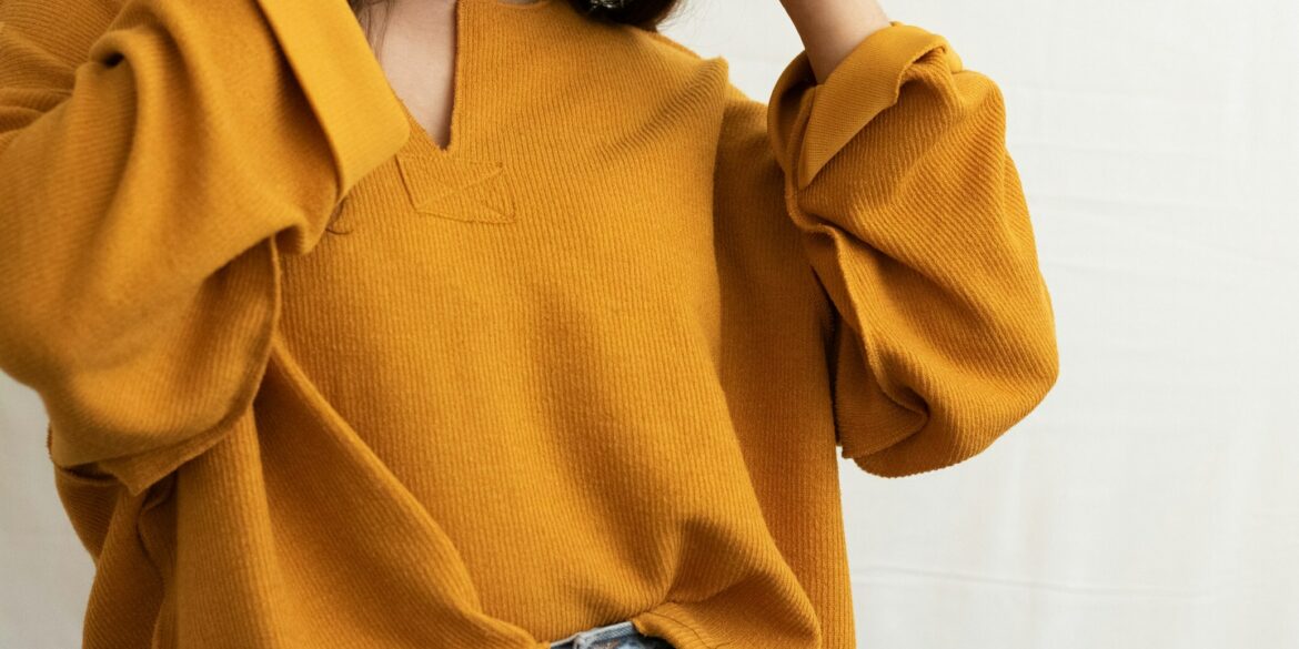 a woman in a yellow sweater is holding her head