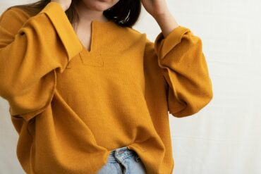 a woman in a yellow sweater is holding her head