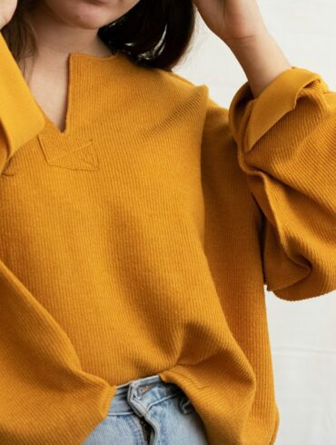 a woman in a yellow sweater is holding her head