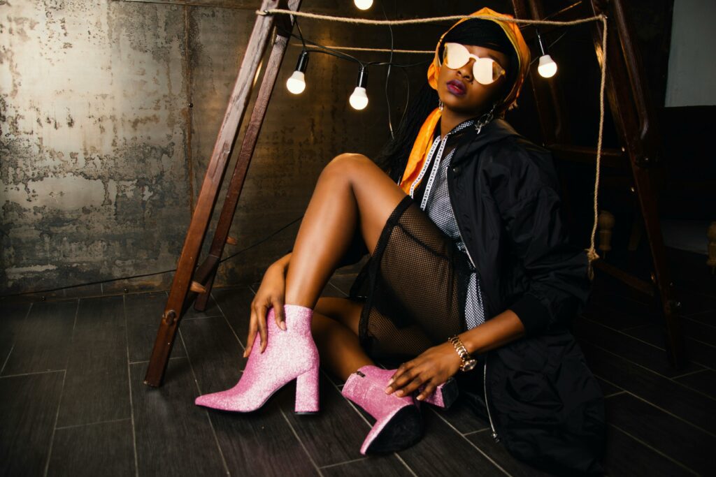 Woman wearing pink sequin ankle boots and sunglasses with glowing light bulbs