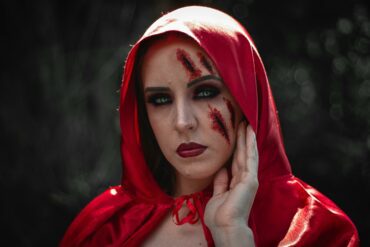 Woman in red hood with fake bruise and cut makeup on her face