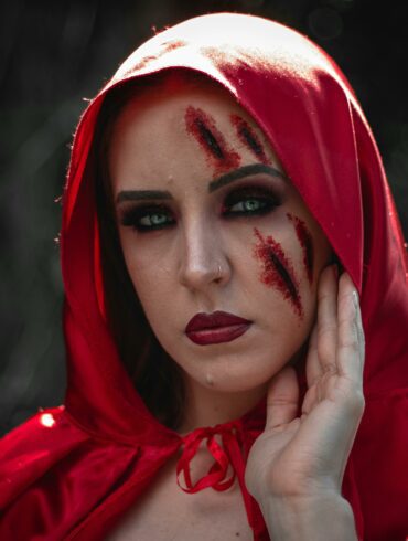 Woman in red hood with fake bruise and cut makeup on her face