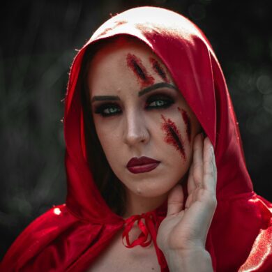 Woman in red hood with fake bruise and cut makeup on her face